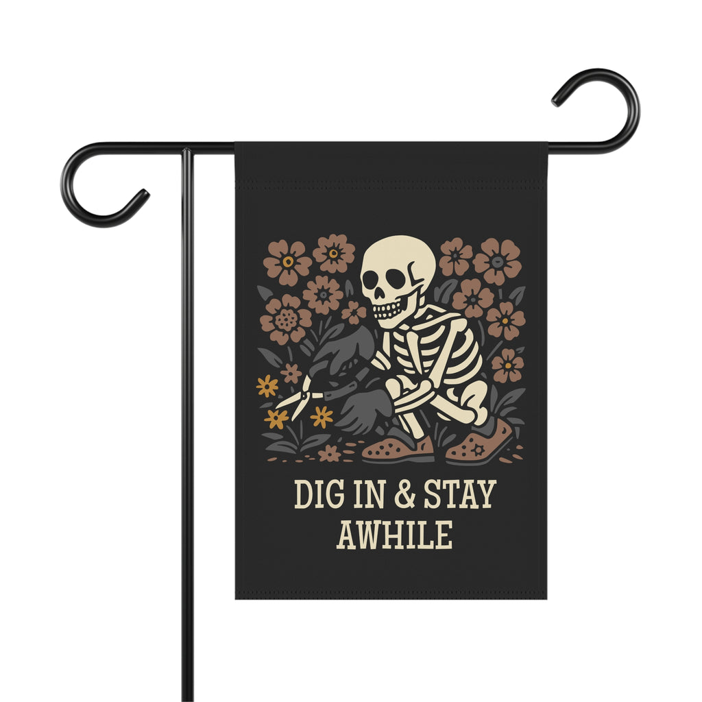 Garden flag with a skeleton and flowers design and 'Dig In & Stay Awhile' text on a black background.