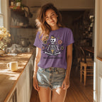 Model wearing the purple 'Bee Whisperer' skeleton t-shirt paired with denim shorts in a sunlit kitchen.