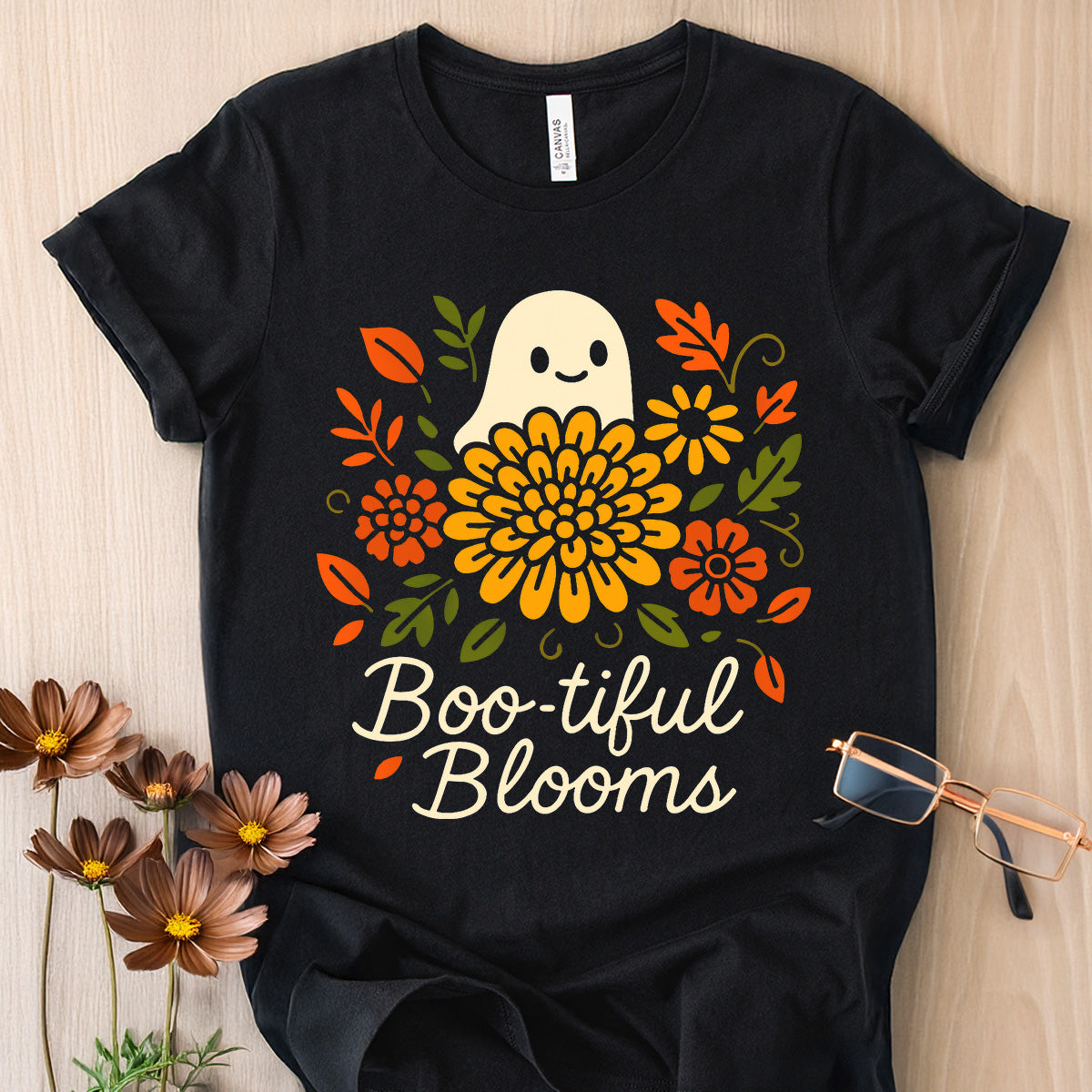 Black t-shirt with a ghost and floral design labeled 'Boo-tiful Blooms' on a wooden surface.