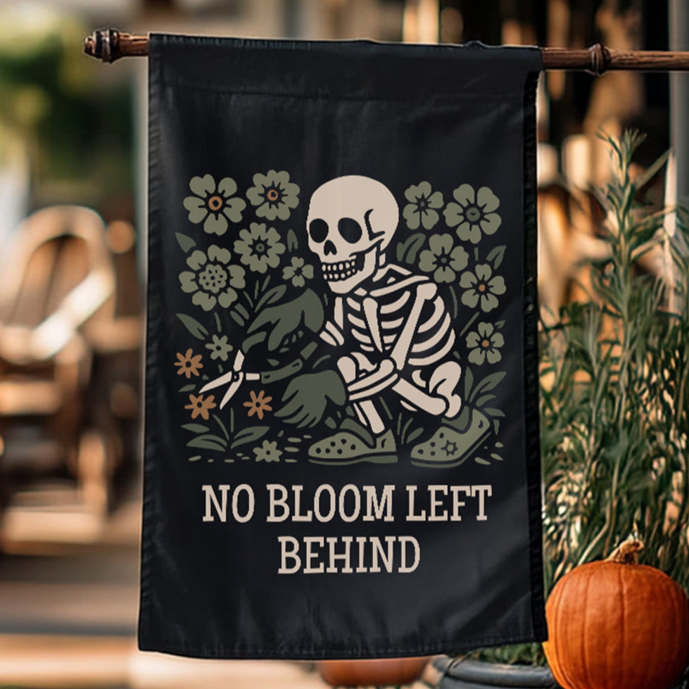 Decorative flag with a skeleton and floral design, featuring the text 'No Bloom Left Behind', hanging outdoors.