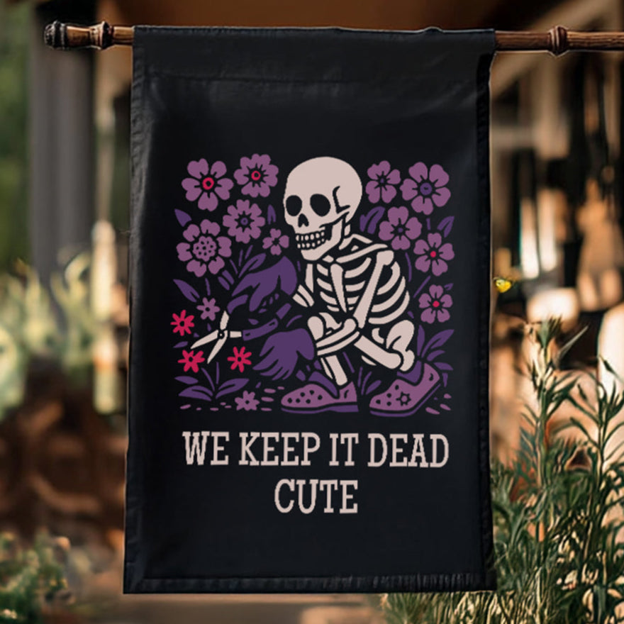 Decorative flag with skeleton and flowers design hanging outdoors.