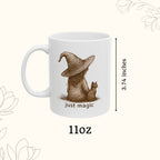 White mug with a design of a bear wearing a witch hat and text 'just magic' on a white background.