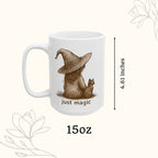 White mug with a brown illustration of a person in a witch hat and a cat, with 'just magic' text, on a white background.